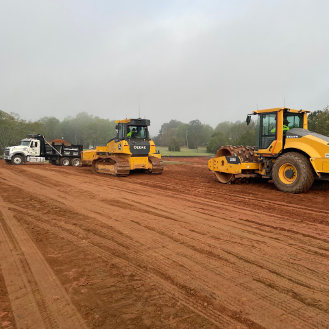 A skilled equipment operator executing precision site grading and building pad preparation for a commercial development project.